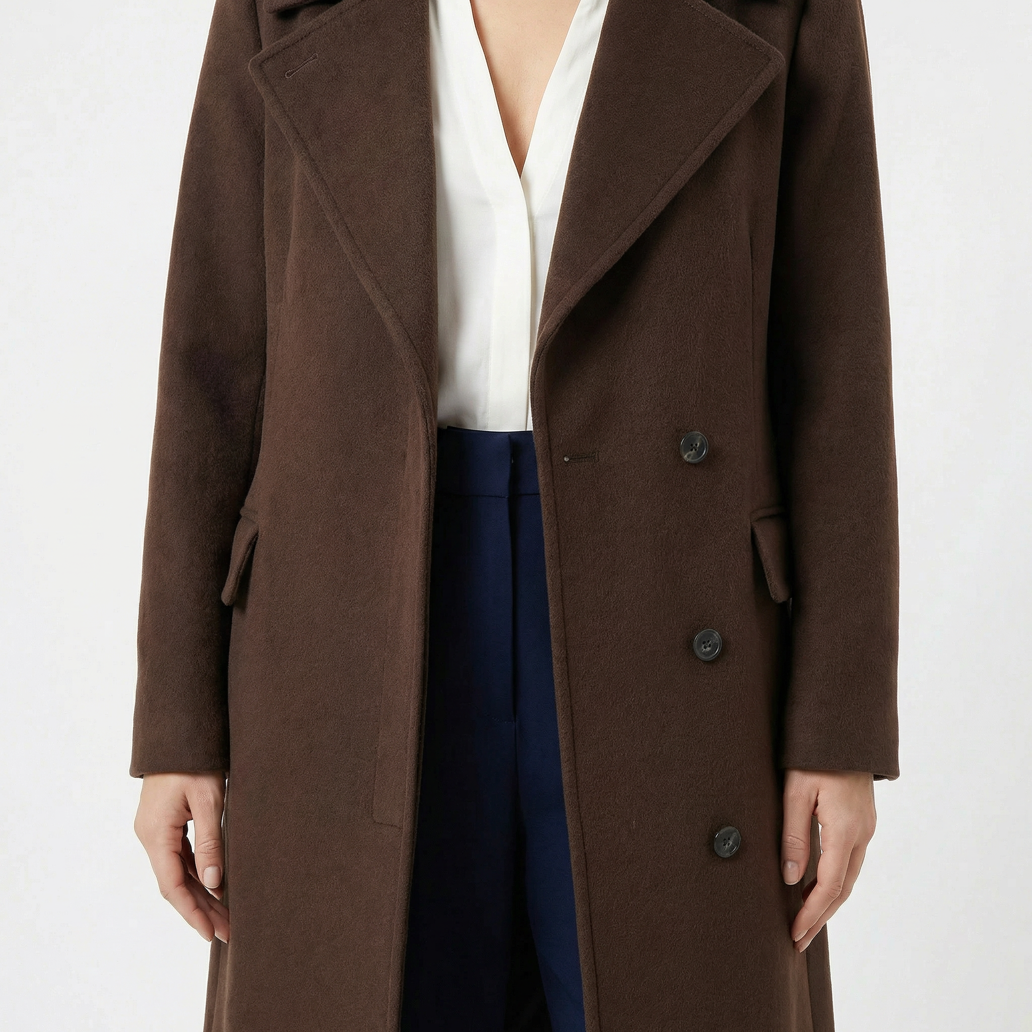 Woman wearing a brown wool double-breasted long coat over white blouse and navy pants